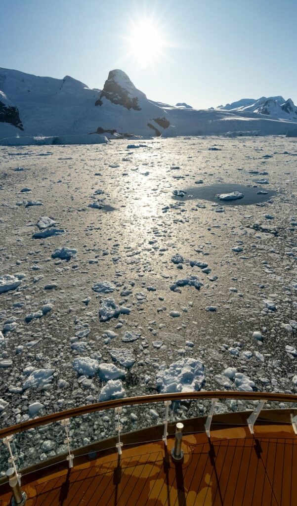 View of icebergs and mountains from a ship in Antarctica's pristine waters.